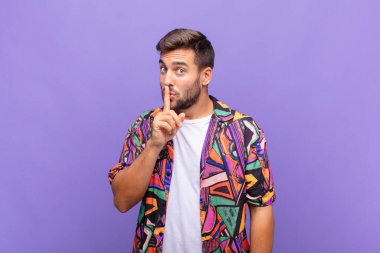 Genç adam sessizlik ve sessizlik istiyor, parmaklarıyla ağzının önünde işaret ediyor, 