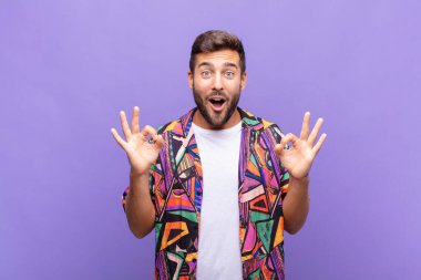 Delikanlı şok olmuş, şaşırmış ve şaşırmış hissediyor. Onaylıyor. İki eliyle de onay işareti yapıyor.