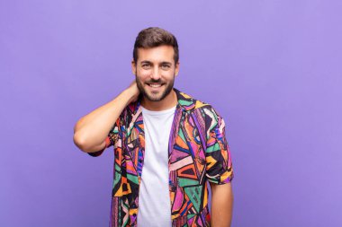 Genç adam neşeli ve kendinden emin bir şekilde gülüyor. Sıradan, mutlu, dostane bir gülümsemeyle.