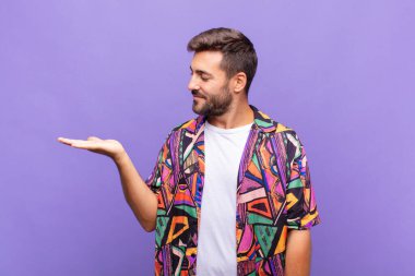 Genç adam kendini mutlu hisseder ve gelişigüzel gülümser. Elinde tuttuğu bir nesneye ya da konsepte bakar.