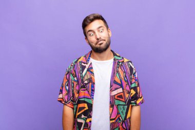 Genç adam şapşal ve komik görünüyor. Şaşı bakışlı, şakacı ve şakacı.