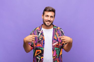 Genç adam gururlu, pozitif ve iki eliyle göğsünü gösteren
