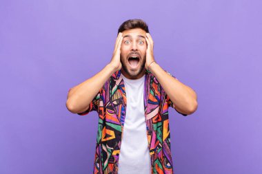 Genç adam el ele tutuşuyor, ağzı açık, son derece şanslı, şaşırmış, heyecanlı ve mutlu hissediyor.