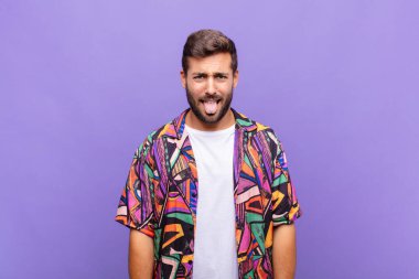 Genç adam tiksinmiş ve sinirlenmiş hissediyor, dilini dışarı çıkarıyor, iğrenç ve iğrenç bir şeyden hoşlanmıyor.