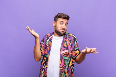 young man shrugging with a dumb, crazy, confused, puzzled expression, feeling annoyed and clueless