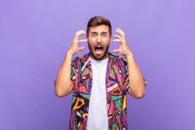 Genç adam elleri havada bağırıyor, öfkeli, sinirli, stresli ve üzgün hissediyor.