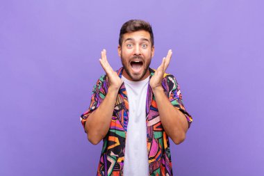 Genç adam beklenmedik bir sürprizden dolayı şaşkın, heyecanlı, gülen, şaşkın ve mutlu hissediyor.