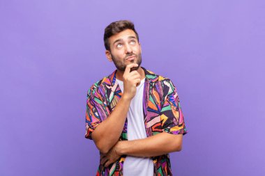 Genç adam düşünüyor, kuşkulu ve şaşkın hissediyor, farklı seçeneklerle, hangi kararı vereceğini merak ediyor.