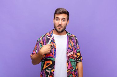 Genç adam şaşkın, şaşkın ve güvensiz hissediyor, kendini göstererek kim olduğunu soruyor, ben mi??