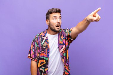 Genç adam şaşkın ve şaşırmış hissediyor, şaşırmış ve hayranlıkla yukarı bakıyor, şaşkın, açık ağızlı bir bakışla