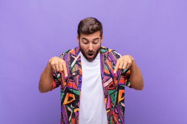 Genç adam şok olmuş, ağzı açık ve şaşkın, inançsızlık ve şaşkınlık içinde bakıyor ve onu işaret ediyor.