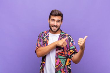 Genç adam neşeyle gülümsüyor ve yan taraftaki fotokopi alanını gösteriyor, mutlu ve tatmin olmuş hissediyor.