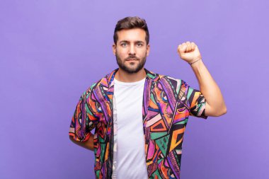 Genç adam kendini ciddi, güçlü ve asi hissediyor, yumruğunu kaldırıyor, protesto ediyor ya da devrim için savaşıyor.