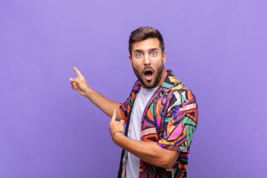 Delikanlı şaşkın ve şaşırmış hissediyor. Kenardaki fotokopi alanını işaret ediyor. Şaşırmış ve ağzı açık bakıyor.