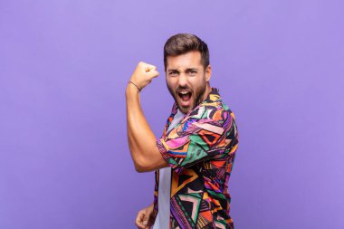 Genç adam kendini mutlu, tatmin olmuş ve güçlü hissediyor, kaslı ve formda, spor salonundan sonra güçlü görünüyor.