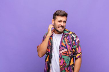 Genç adam stresli, hayal kırıklığına uğramış ve yorgun, endişeli ve sorunlu bir bakışla boynunu ovalıyor.