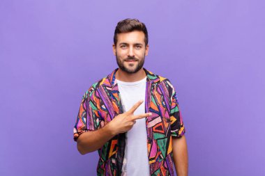 Genç adam mutlu, pozitif ve başarılı hissediyor, göğsünün üzerinde el yapımı V ile zafer ya da barış gösteriyor.