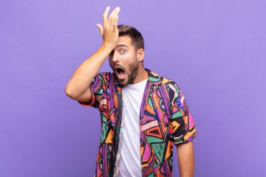 young man raising palm to forehead thinking oops, after making a stupid mistake or remembering, feeling dumb