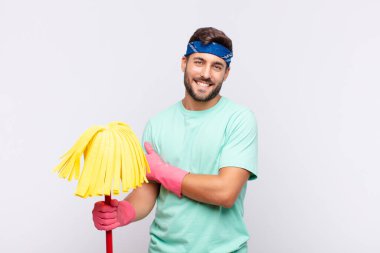 Genç adam utangaç ve neşeli bir şekilde gülüyor, arkadaş canlısı ve olumlu ama güvensiz bir tavırla.