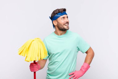 Genç adam mutlu, neşeli ve kendinden emin görünüyor, gururla gülümsüyor ve iki elini de kalçasında istiyor.