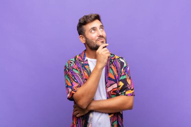 Genç adam düşünceli, meraklı ya da hayal kuruyor, hayal kuruyor ve uzayı kopyalamak için yukarı bakıyor.