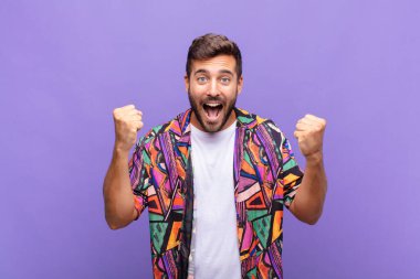 Genç adam mutlu, pozitif ve başarılı hissediyor, zaferi, başarıları ya da iyi şansı kutluyor.