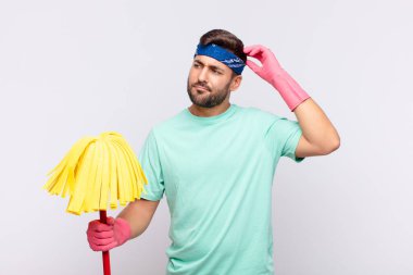 Genç adam şaşkın ve şaşkın hissediyor, başını kaşıyor ve yana bakıyor.