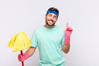 Genç adam mutlu bir şekilde gülümsüyor ve yan bakıyor, merak ediyor, düşünüyor ya da bir fikri var.