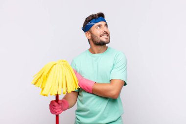 Genç adam mutlu, gururlu ve umutlu, merak ediyor ya da düşünüyor, çapraz kollarla uzayı taklit ediyor.