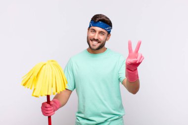 Genç adam gülümsüyor ve mutlu görünüyor, kaygısız ve pozitif, tek elle zafer ya da barış işareti yapıyor.