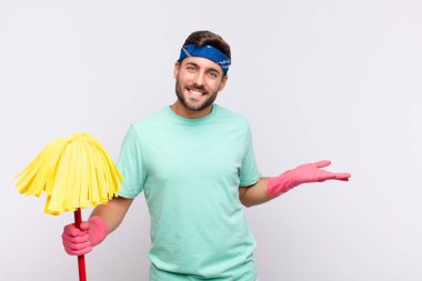 Genç adam gülümsüyor, mutlu, pozitif ve tatmin olmuş hissediyor, fotokopi alanında nesne veya konsept tutuyor veya gösteriyor