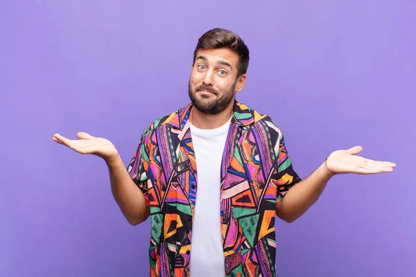 Genç adam şaşkın ve şaşkın hissediyor, şüpheci, farklı seçenekleri tartıyor veya komik bir ifadeyle seçiyor.