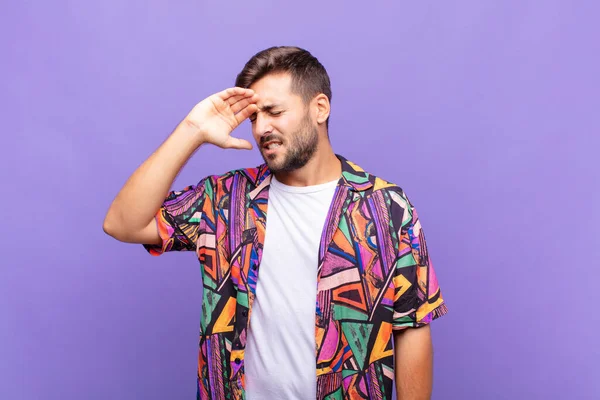 Genç adam stresli, yorgun ve hayal kırıklığına uğramış görünüyor, alnından ter damlıyor, umutsuz ve bitkin hissediyor.