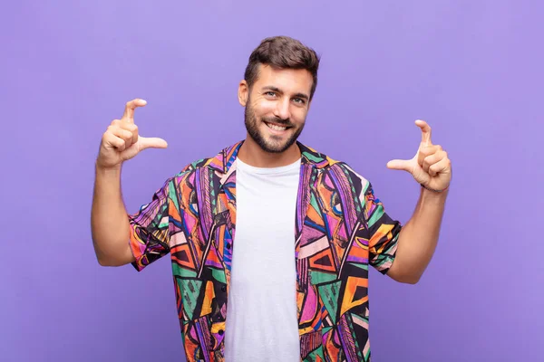 Genç adam kendi gülüşünü iki eliyle çiziyor, olumlu ve mutlu görünüyor, sağIık kavramı