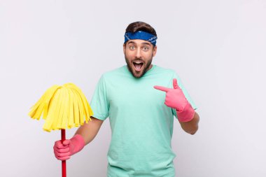 Genç adam mutlu, şaşkın ve gururlu, heyecanlı, şaşkın bakışlarla kendini işaret ediyor.