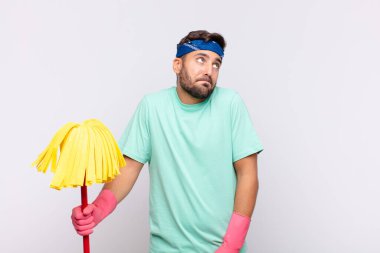 Genç adam omuz silkiyor, kafası karışık ve kararsız, kolları bağlı ve şaşkın bir şekilde şüpheli bakıyor.