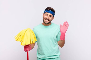 Genç adam mutlu ve neşeyle gülümsüyor, el sallıyor, seni selamlıyor ve selamlıyor, ya da hoşça kal diyor.