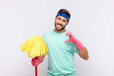 Genç adam gülümsüyor ve mutlu, sevimli, romantik ve aşık, iki eliyle kalbi şekillendiriyor.