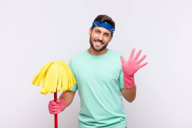 Genç adam gülümsüyor ve arkadaş canlısı görünüyor, 5 ya da 5 numarayı gösteriyor, eli önde, geriye doğru sayıyor.