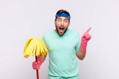 Genç adam gülüyor, mutlu, pozitif ve şaşırmış görünüyor. Yan fotokopi alanını işaret eden harika bir fikrin farkına varıyor.