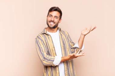 Genç adam gururla ve güvenle gülümsüyor, mutlu ve tatmin olmuş hissediyor ve fotokopi alanında bir konsept gösteriyor.