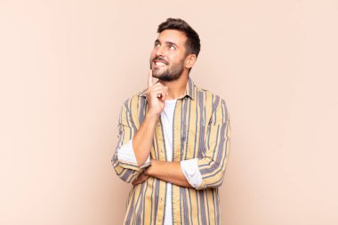 Genç adam mutlu bir şekilde gülümsüyor ve hayal kuruyor ya da şüphe ediyor.