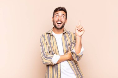 Genç adam mutlu bir şekilde gülümsüyor ve yan bakıyor, merak ediyor, düşünüyor ya da bir fikri var.