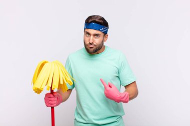 Genç adam şaşkın ve şaşkın bir bakışla kendini işaret ediyor. Seçildiğine şaşırmış ve şaşırmış.