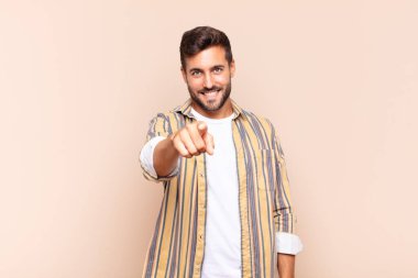 Genç adam kameraya tatmin olmuş, kendinden emin, dostane bir gülümsemeyle bakıyor ve seni seçiyor.