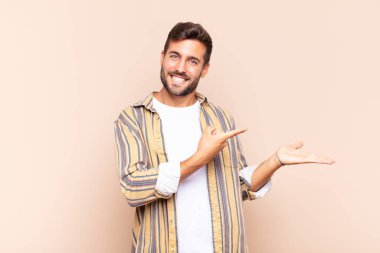 Genç adam gülümsüyor, mutlu, kaygısız ve memnun, fotokopi alanındaki konsepte ya da fikre işaret ediyor.