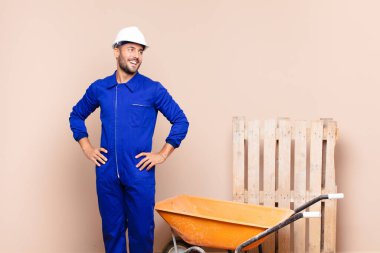 Genç adam mutlu, neşeli ve kendinden emin görünüyor. Gururla gülümsüyor ve kalça inşaatında iki elini de kullanmak istiyor.