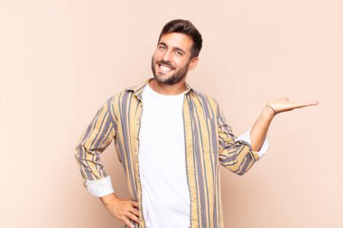 Genç adam gülümsüyor, kendinden emin, başarılı ve mutlu, fotokopi alanında fikir veya konsept gösteriyor.