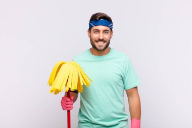 Genç adam pozitif ve kendinden emin bir şekilde gülümsüyor, tatmin olmuş, arkadaş canlısı ve mutlu görünüyor.