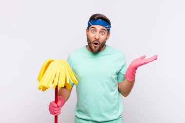 Genç adam şaşırmış ve şok olmuş görünüyor, çenesi düşmüş bir nesneyi elinde açık bir elle tutuyor.